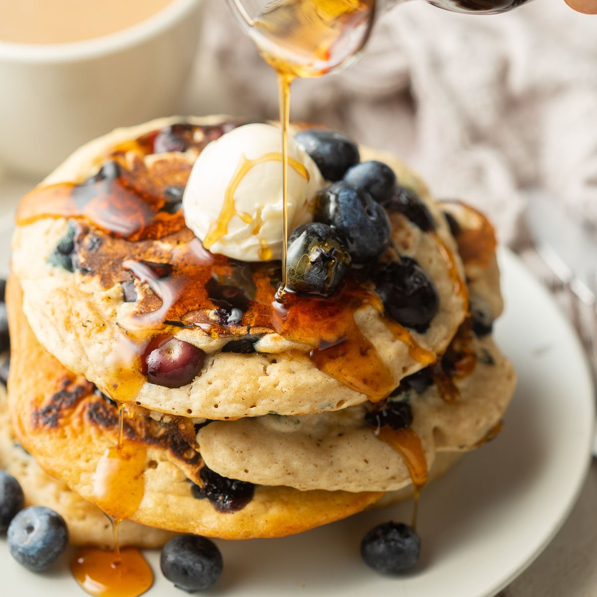 Syrup drizzled over a stack of vegan blueberry pancakes.