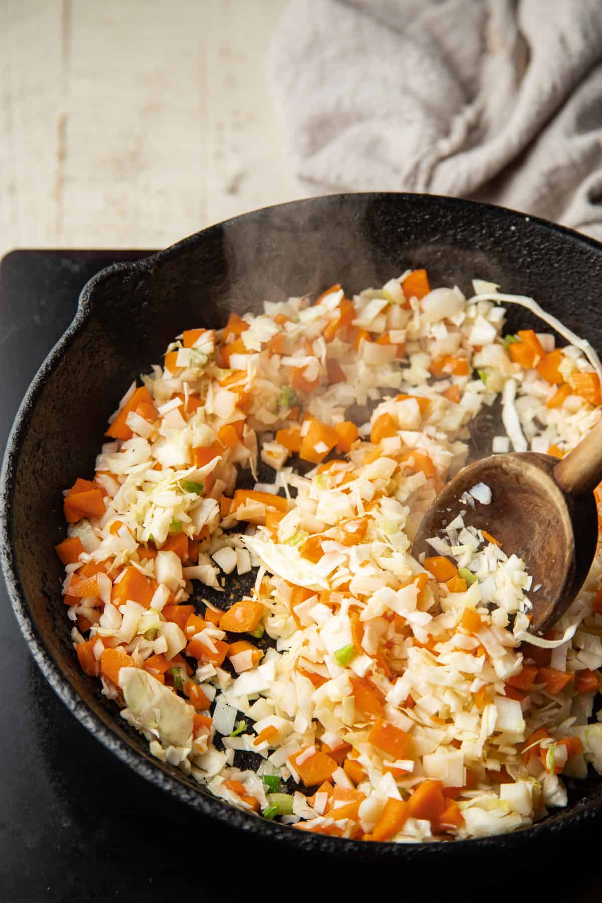 Cabbage, carrots and water chestnuts cooked in a pan.