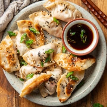 Plate of potstickers with a bowl of dipping sauce.