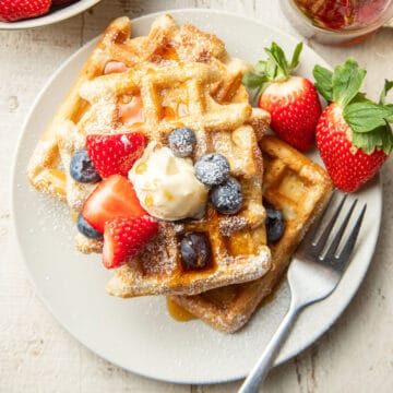 Vegan Waffles on a plate with fork and strawberries.