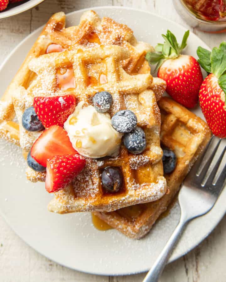 Vegan Waffles on a plate with fork and strawberries.