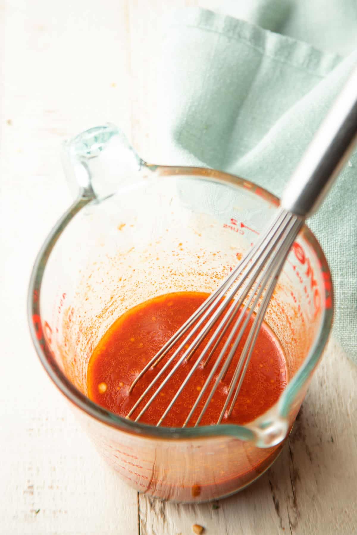 Gochujang sauce in a measuring cup with whisk.