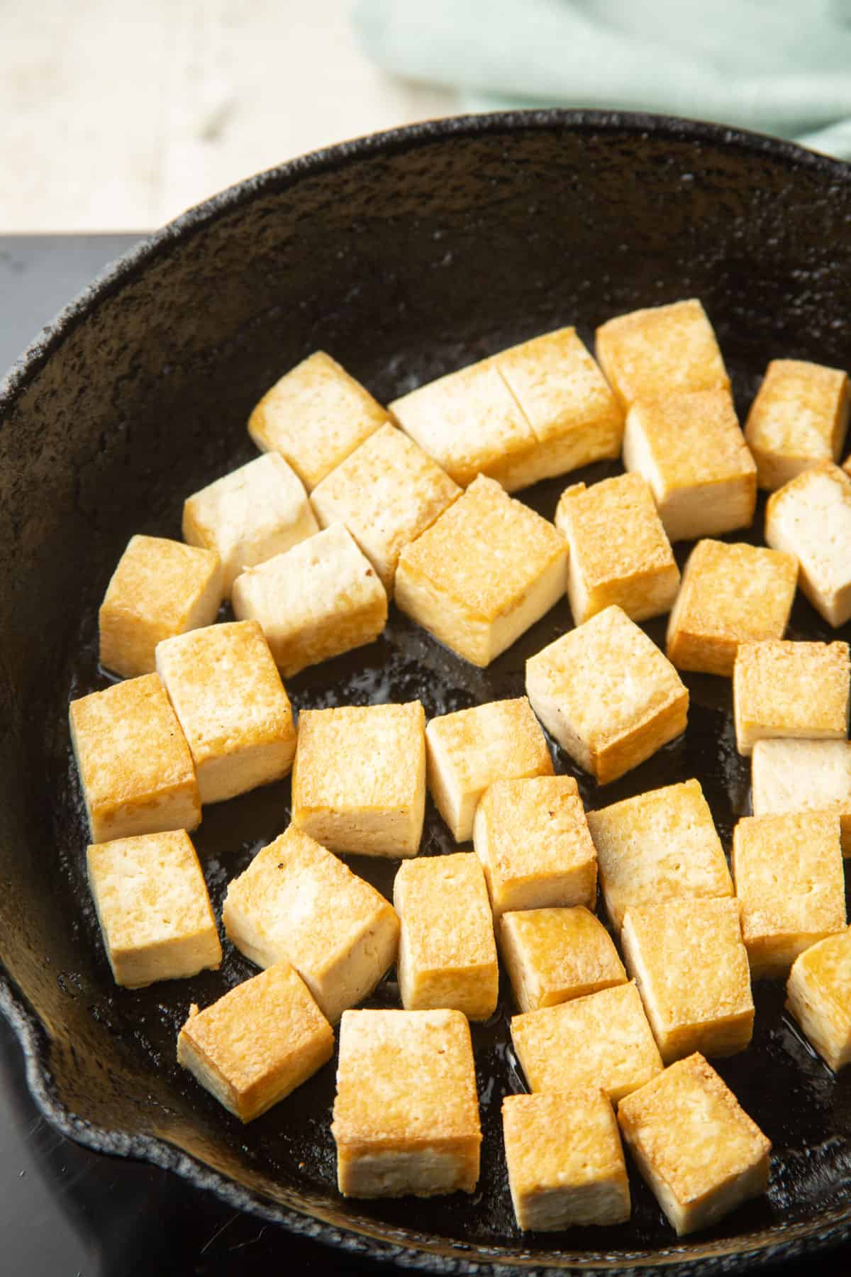 Tofu cubes are cooking in a wok.