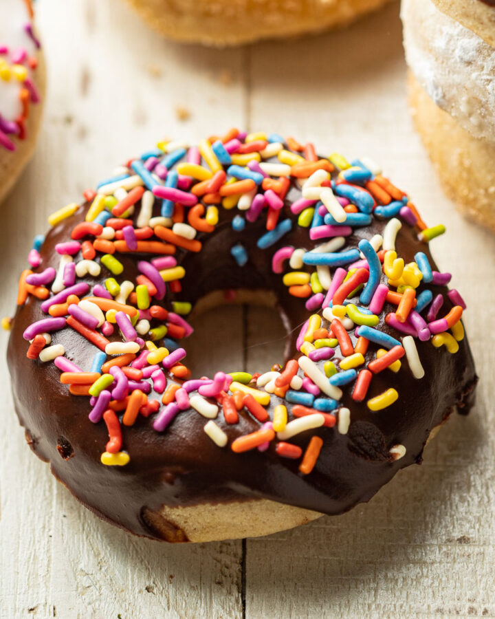 Vegan Baked Doughnut topped with chocolate frosting and rainbow sprinkles.