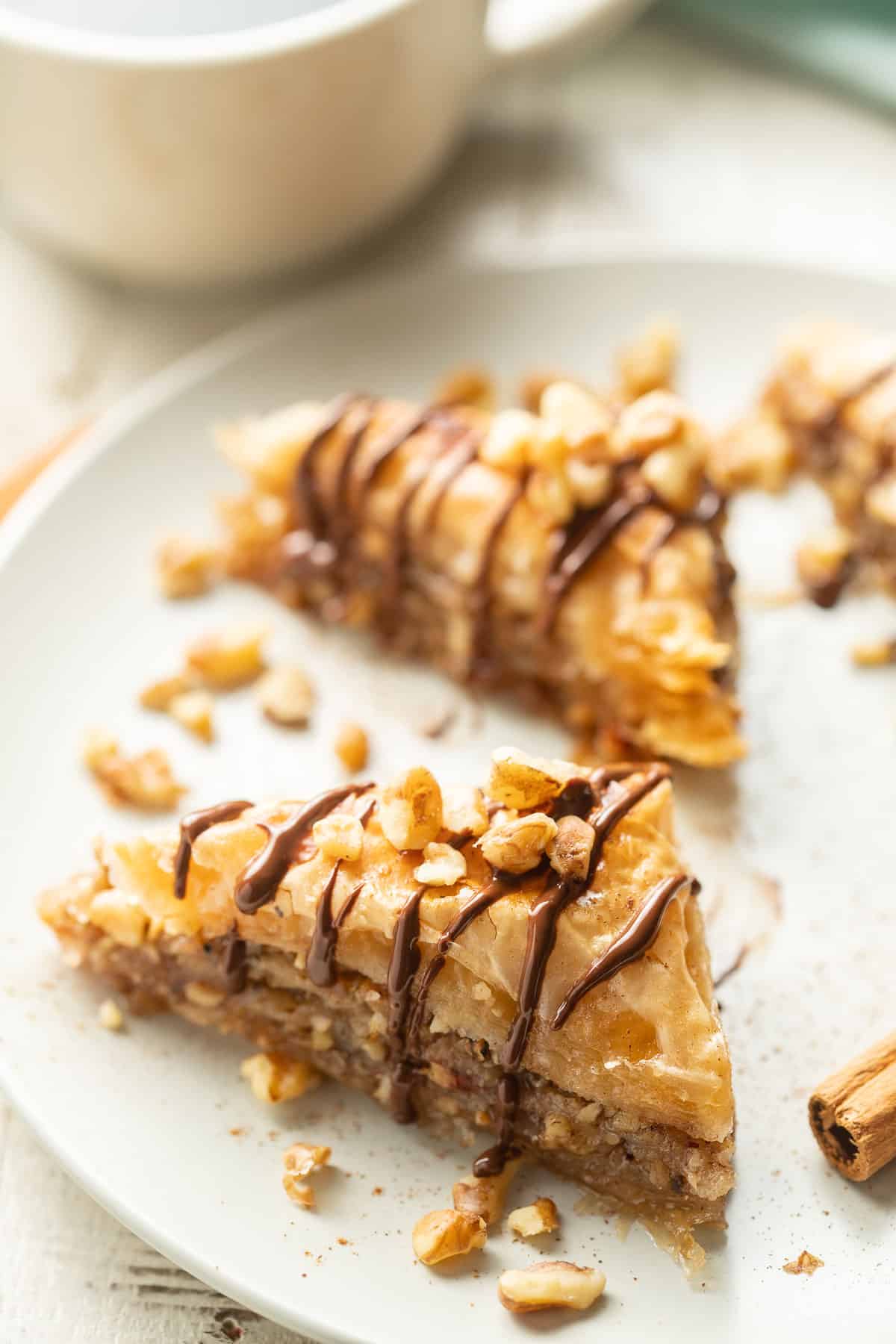Vegan Baklava slices on a dish with coffee cup in the background.