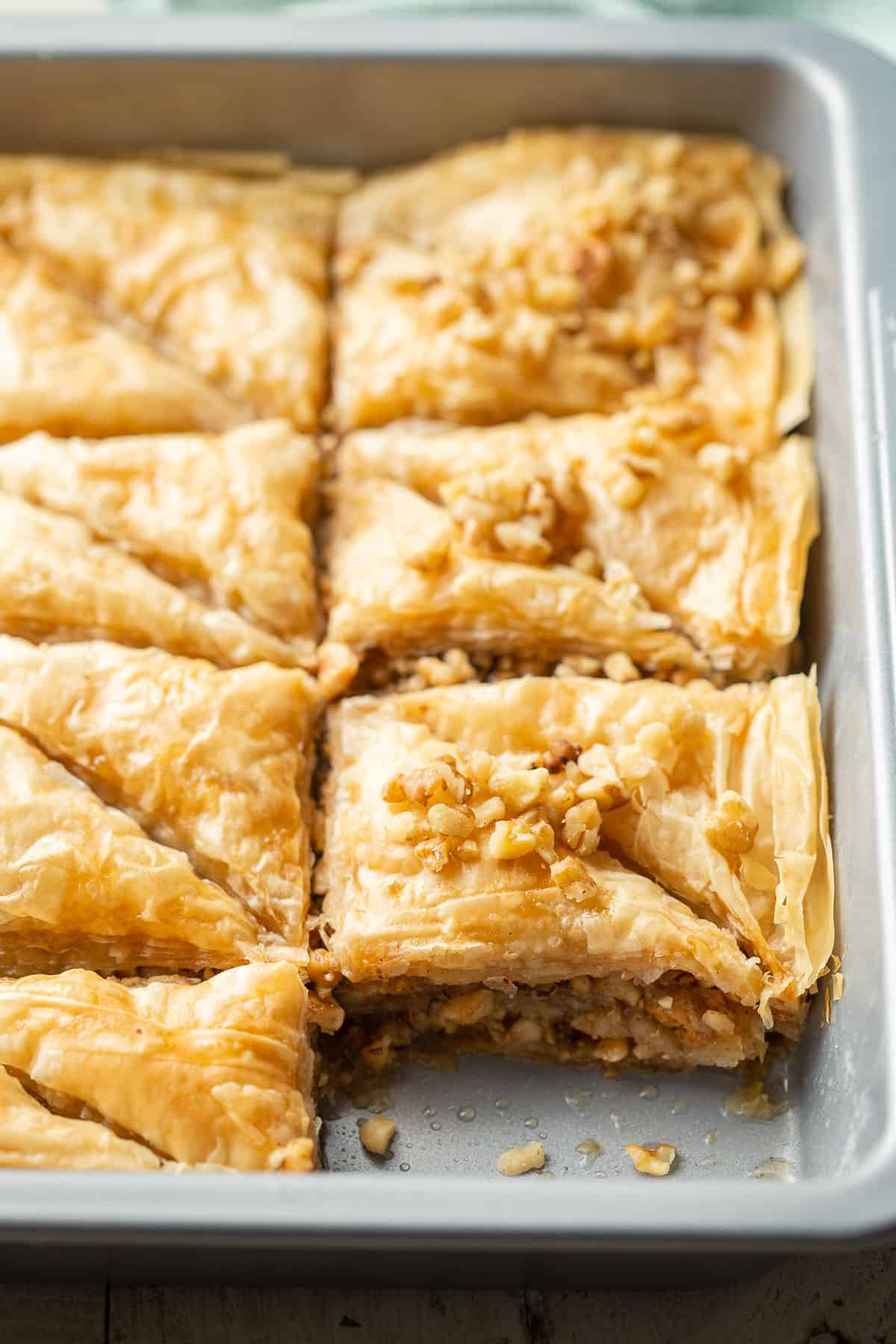 Vegan Baklava topped with nuts in a baking pan.