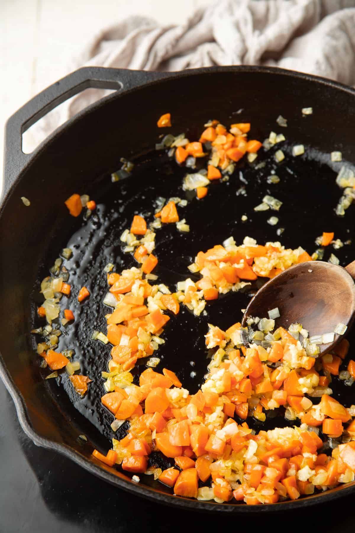Carrots, onions, and garlic cooking in a skillet.