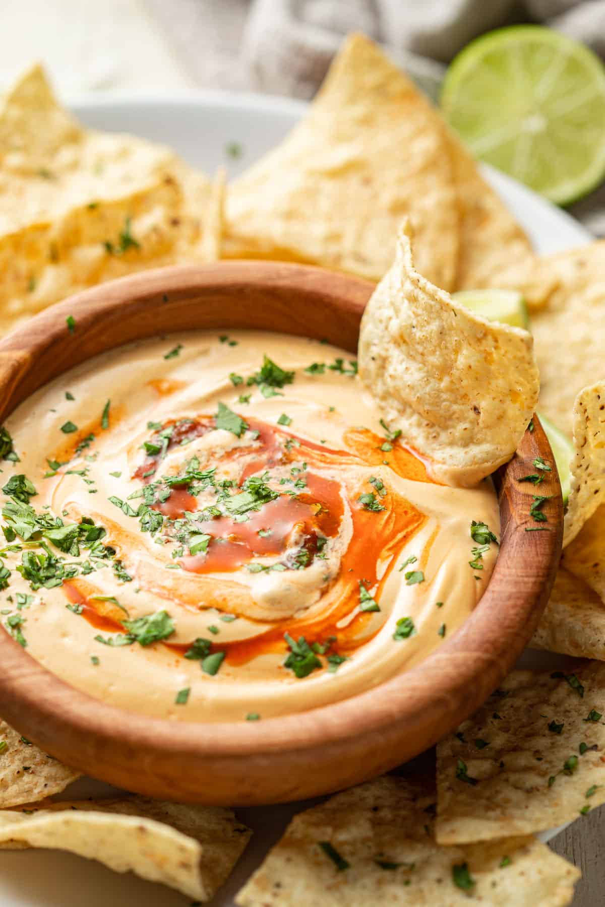 Bowl of Bowl of cashew queso with a chip in it.