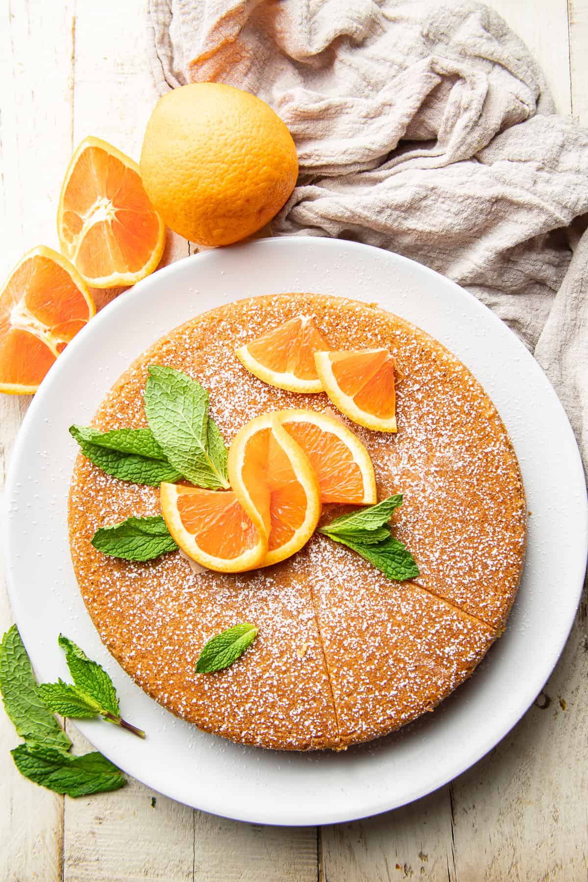 Vegan Orange Olive Oil Cake on a plate with orange slices and mint leaves.