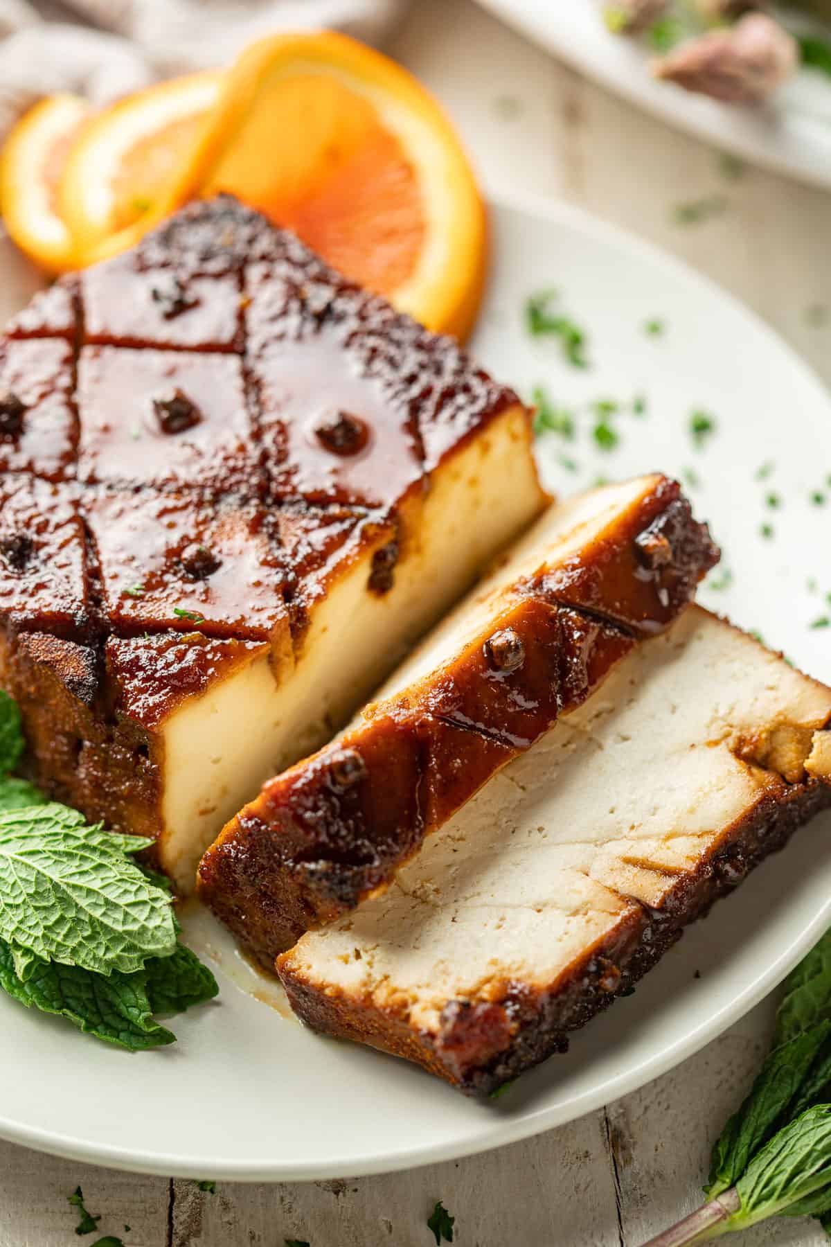 Close up of a partially sliced tofu roast on a plate.