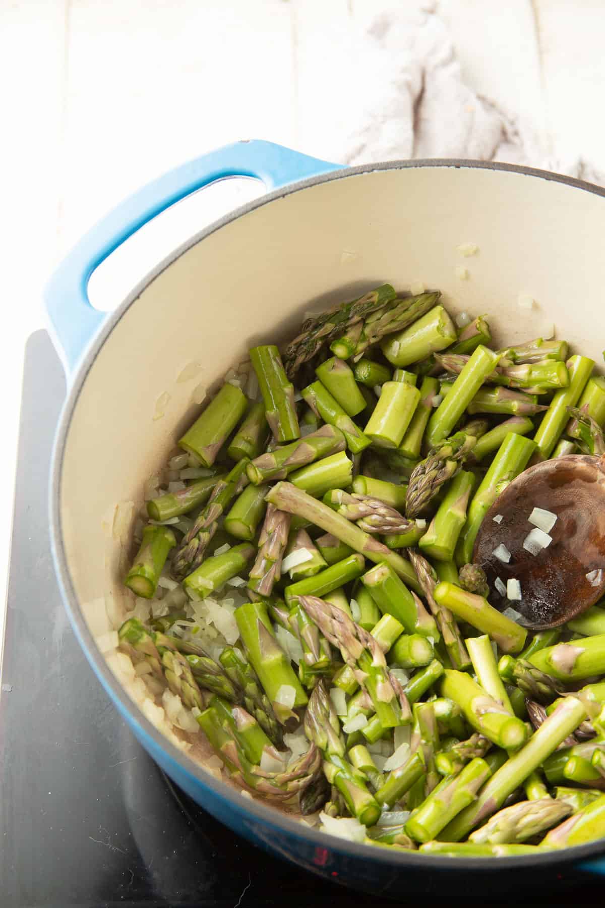 Asparagus pieces and onion cooking in a pot.
