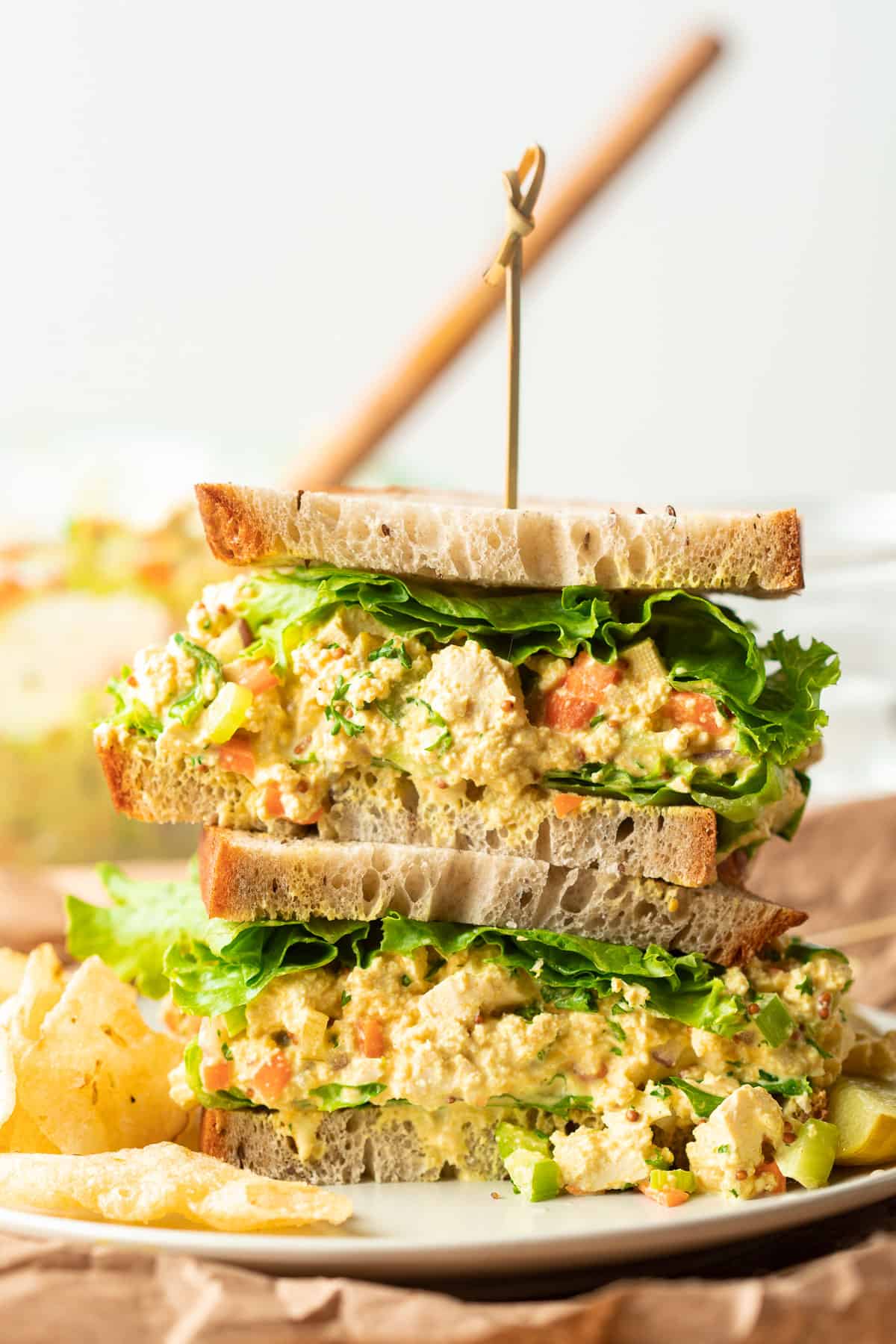 Two halves of a vegan egg salad sandwich are stacked on a plate.