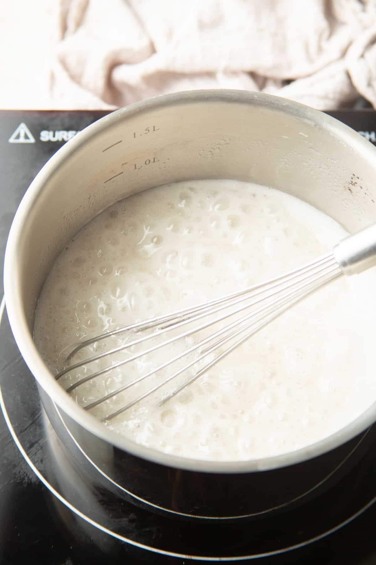 Coconut milk and sugar simmering in a saucepan.