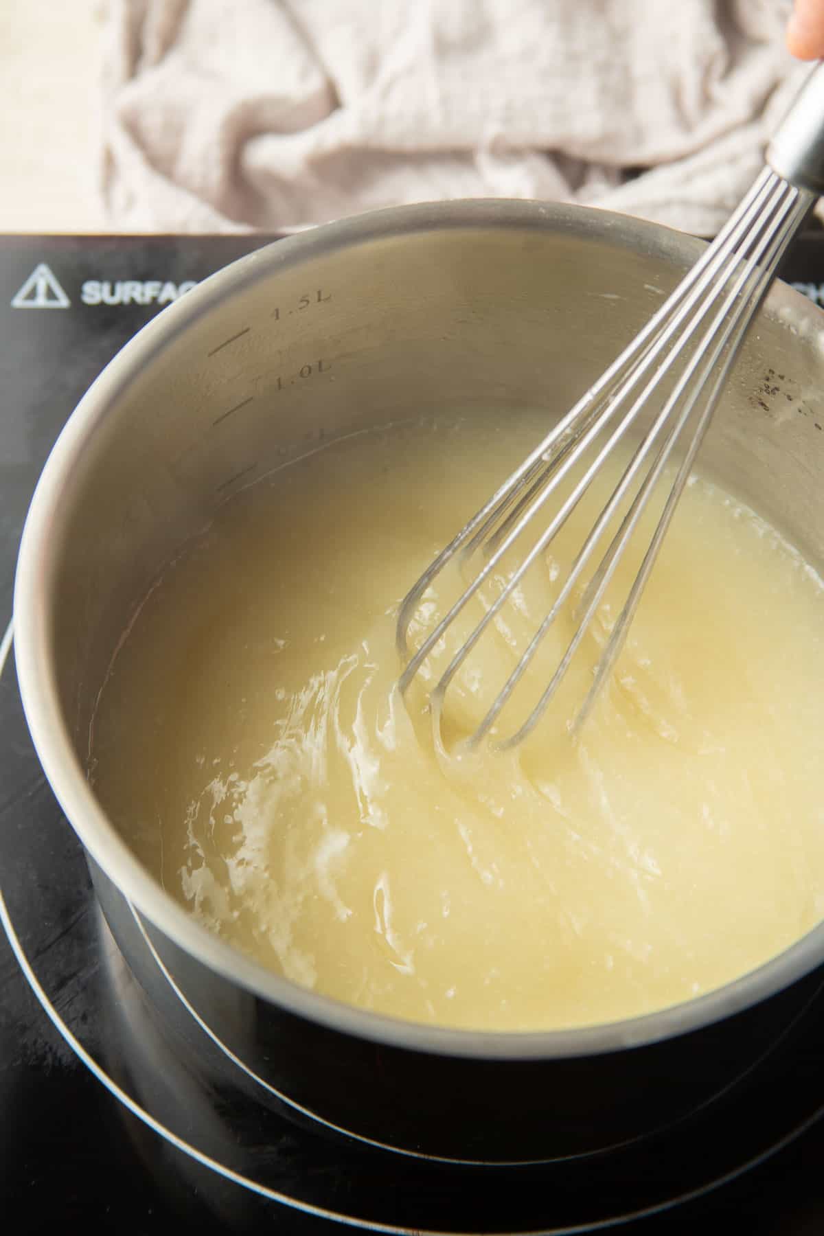 Vegan Lemon Curd simmering in a saucepan.