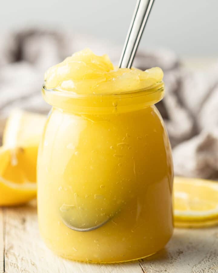 Jar of Vegan Lemon Curd with a spoon in it.