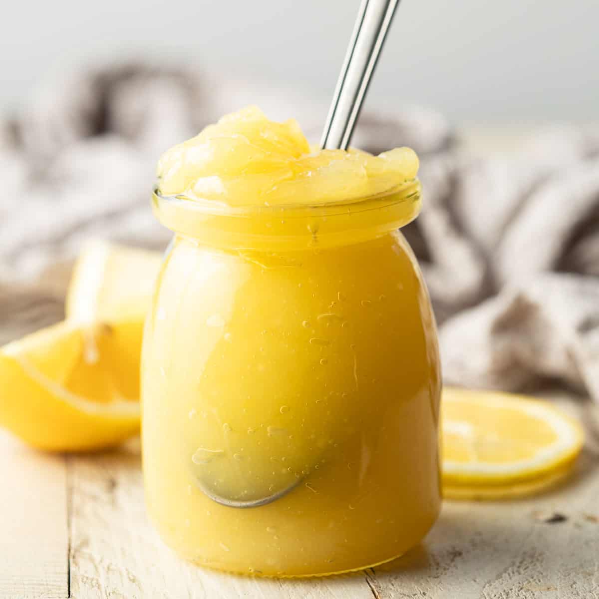 Jar of Vegan Lemon Curd with a spoon in it.