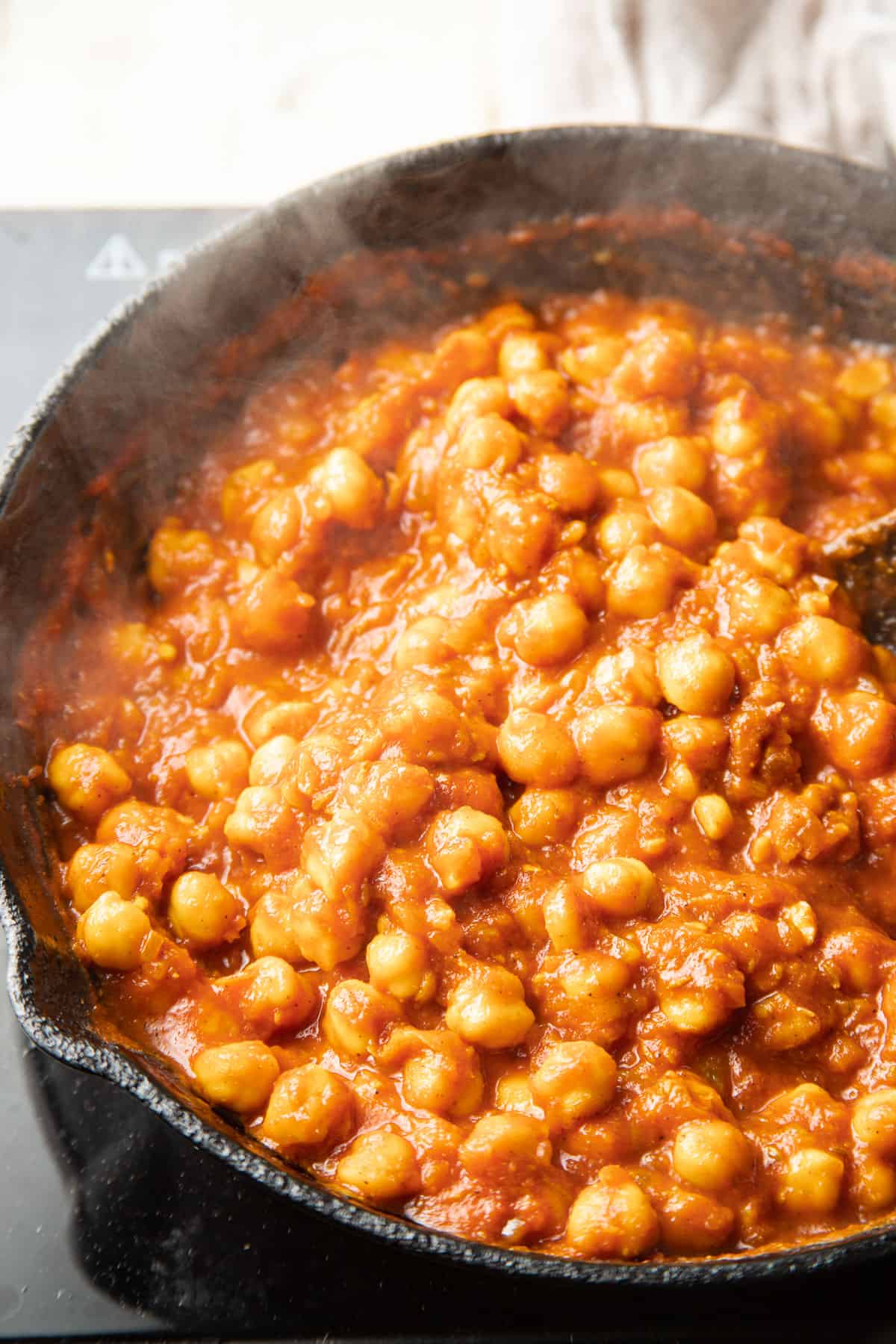 Chickpeas and tomato sauce simmering in a skillet.