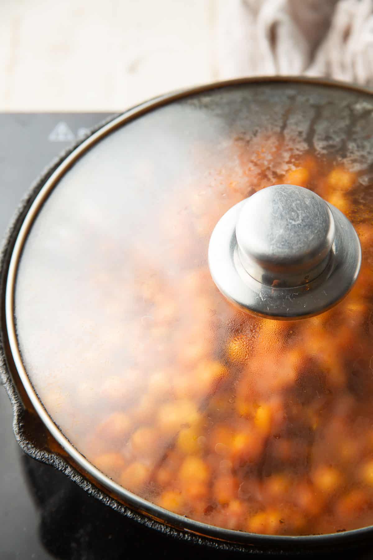 Vegan Chana Masala simmering in a skillet with the lid on.