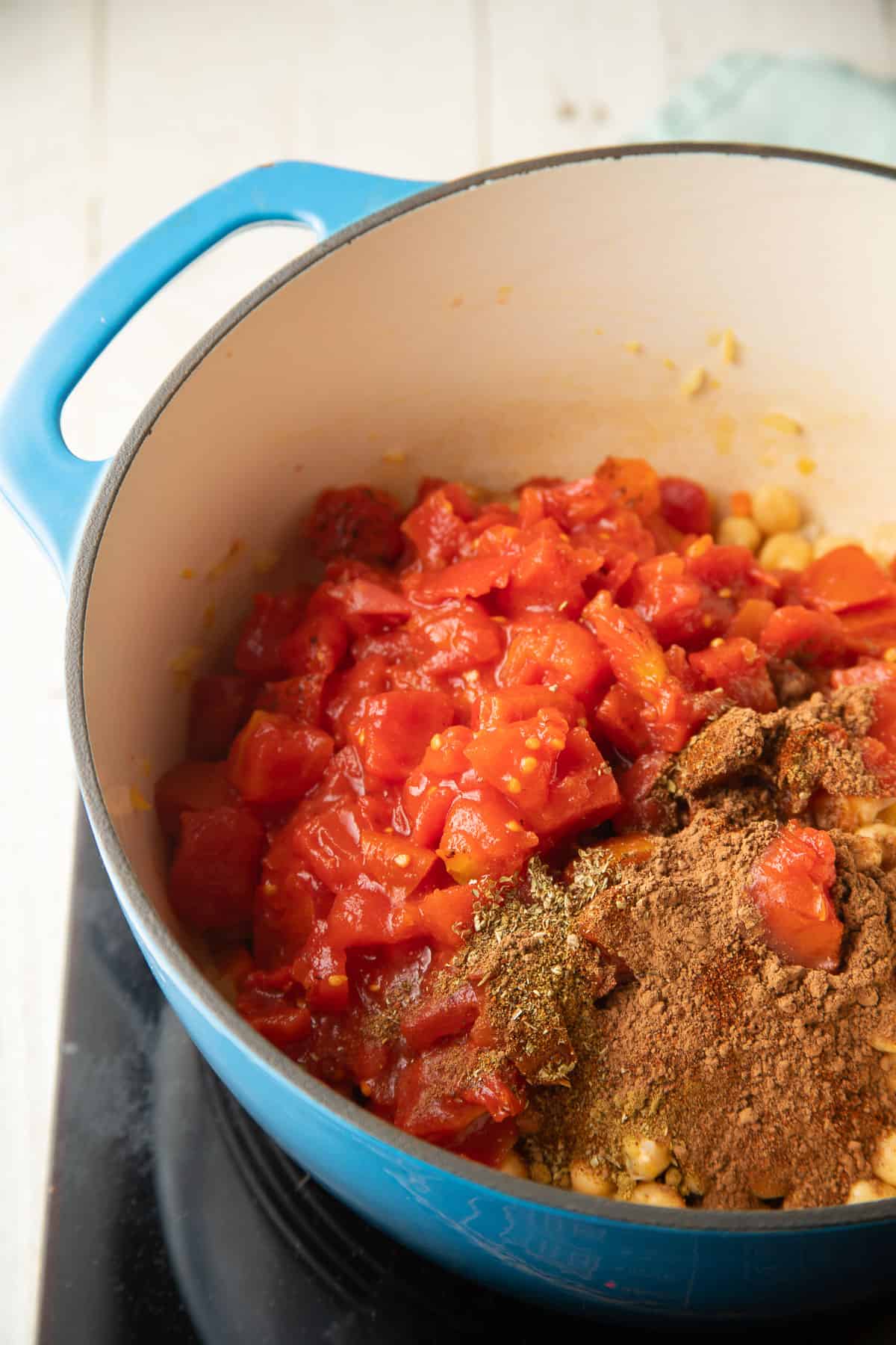 Spices, tomatoes and chickpeas in a pot.