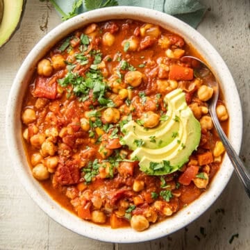 Bowl of Chickpea Chili topped with avocado and chopped fresh cilantro.