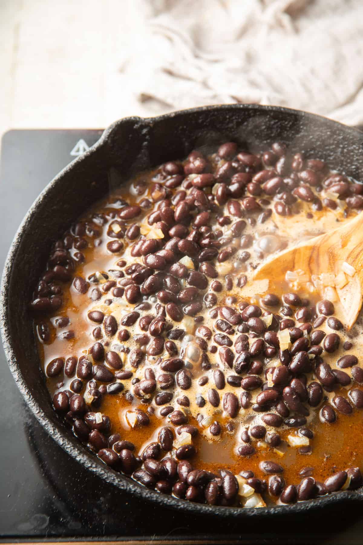 Black beans cooking in a skillet.