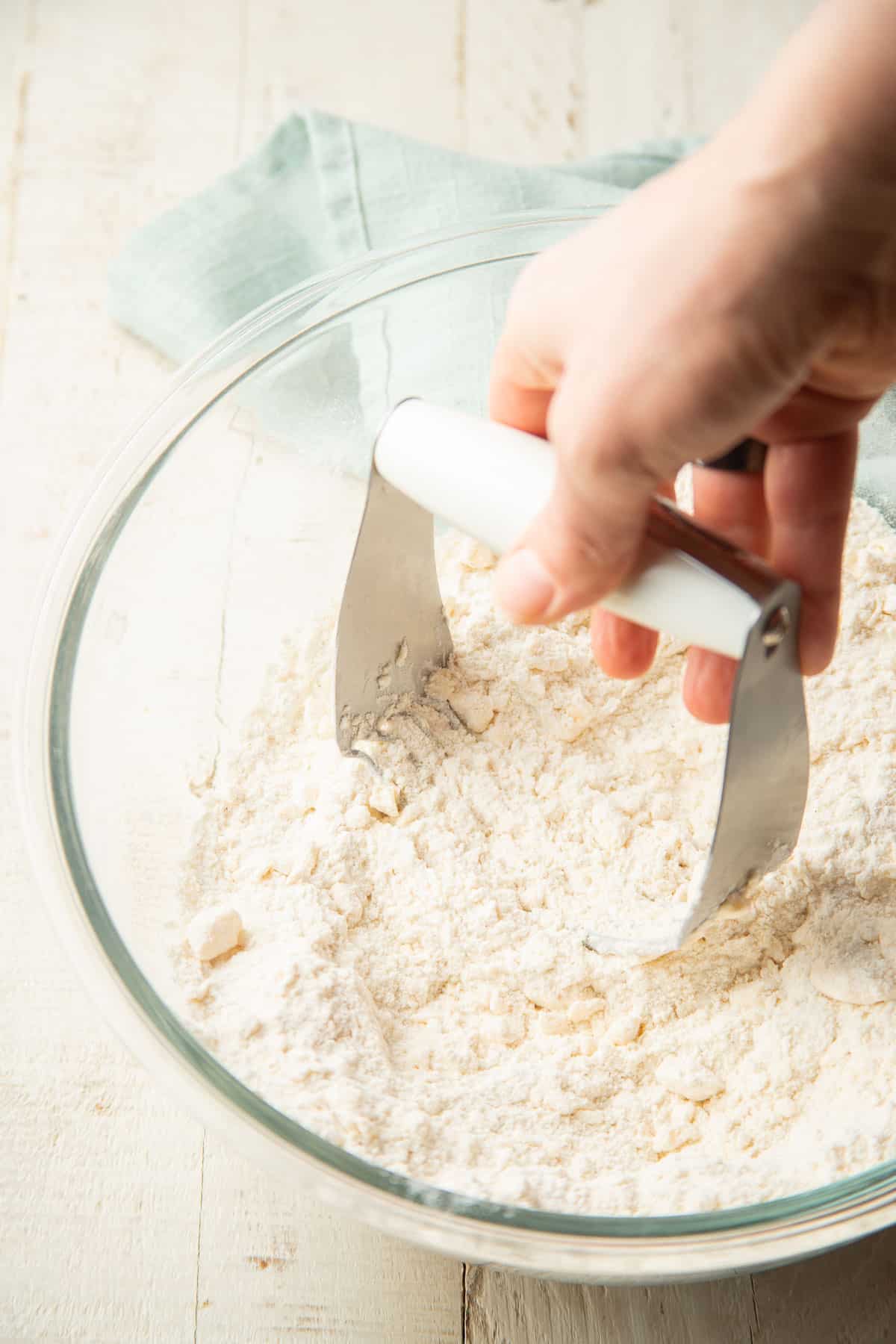 Hand cutting butter into a bowl of dry ingredients for scone dough.