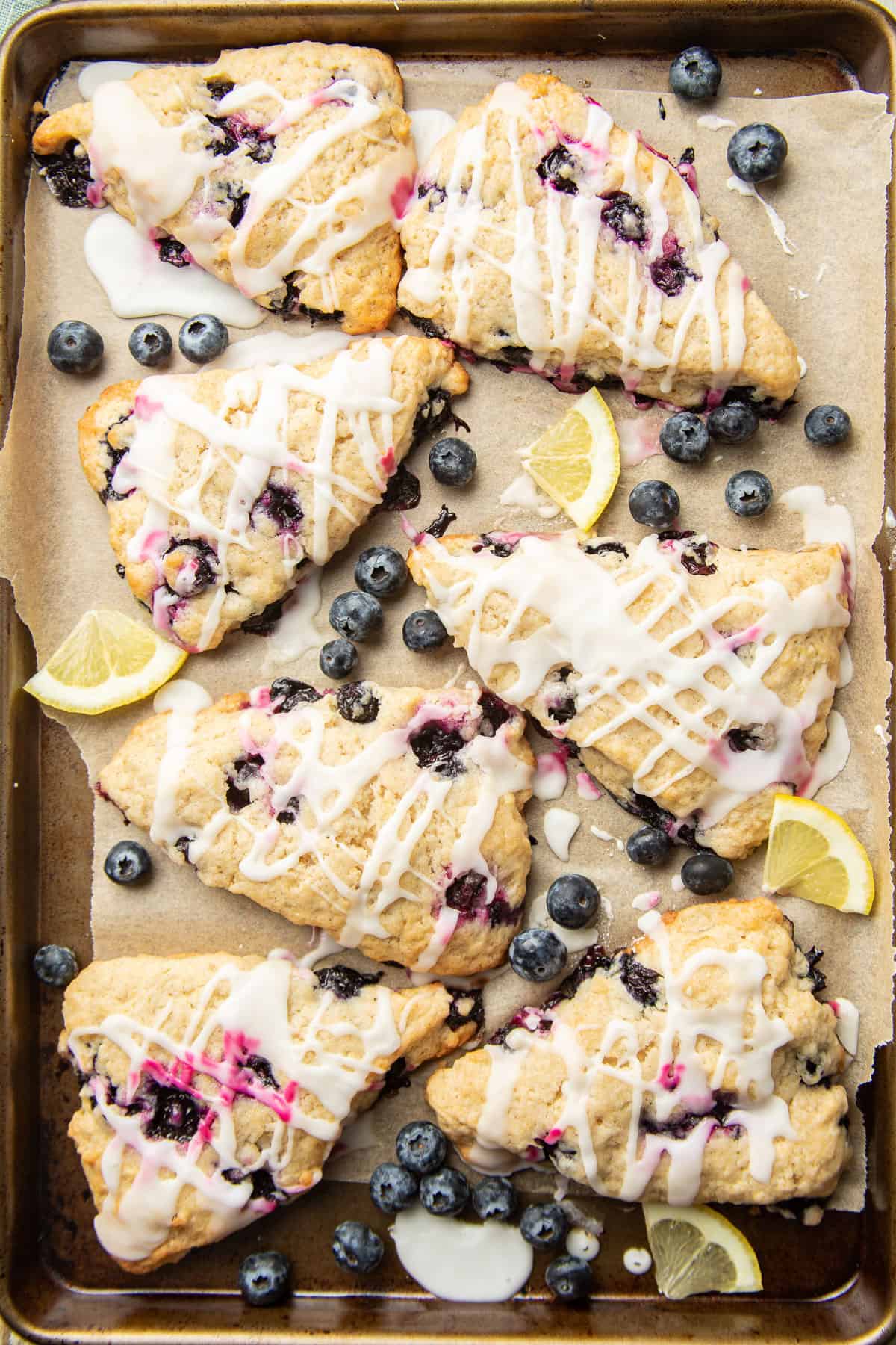 Vegan Blueberry Scones on a baking sheet with blueberries and lemon slices.