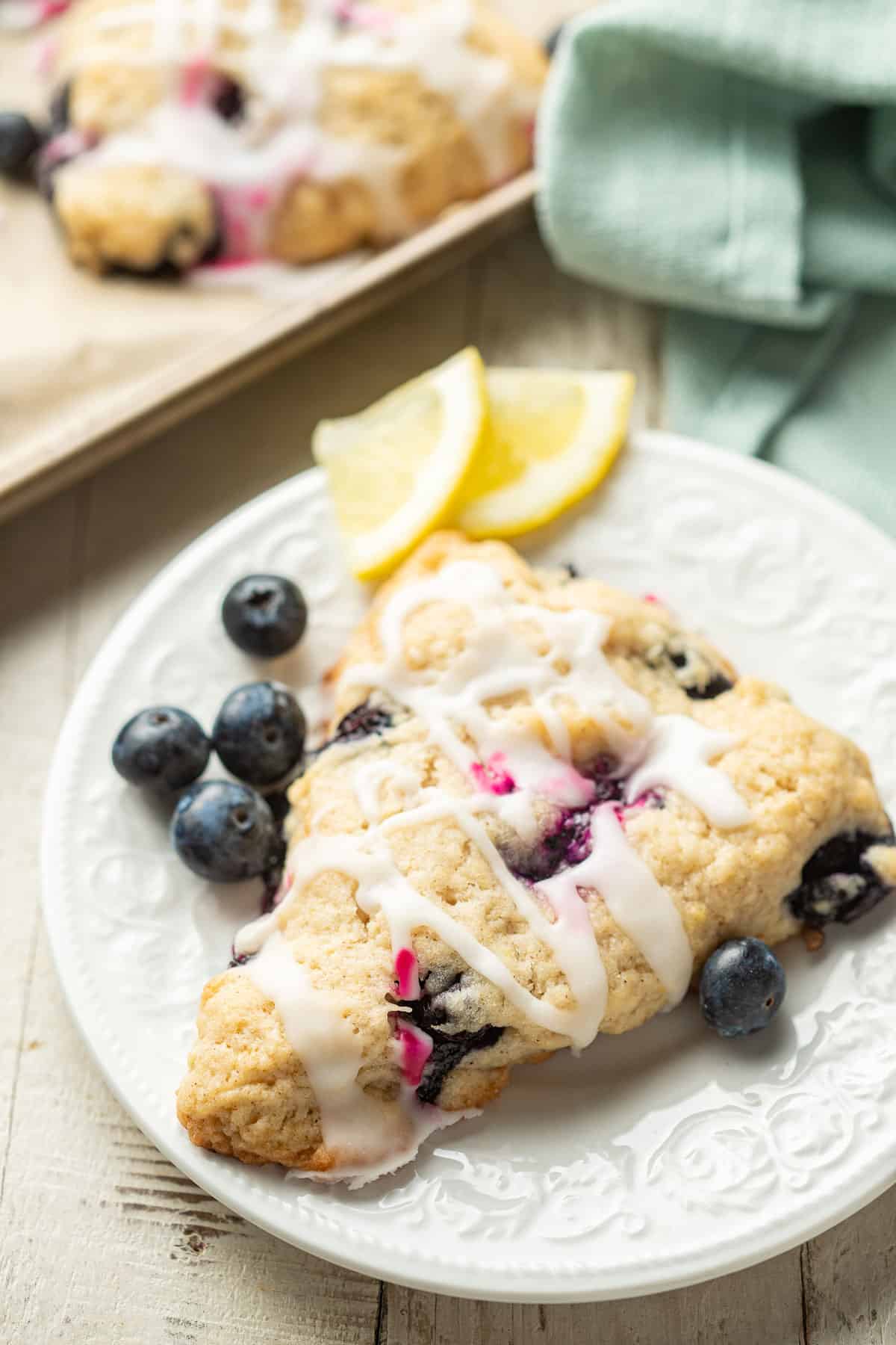 Vegan Blueberry Scone on a plate with a baking sheet in the background.
