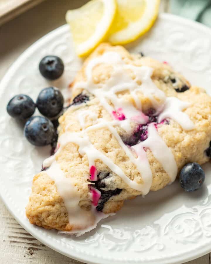 Vegan Blueberry Scone on a plate with blueberries and lemon slices.
