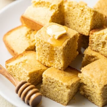 Plate of Vegan Cornbread squares topped with vegan butter and maple syrup.