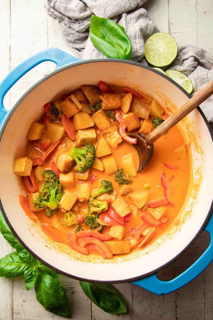 Bowl of vegan red curry with wooden spoon.