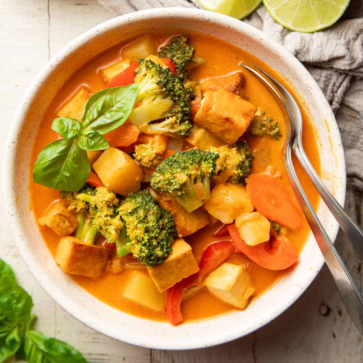 Bowl of vegan red curry topped with fresh basil leaves.