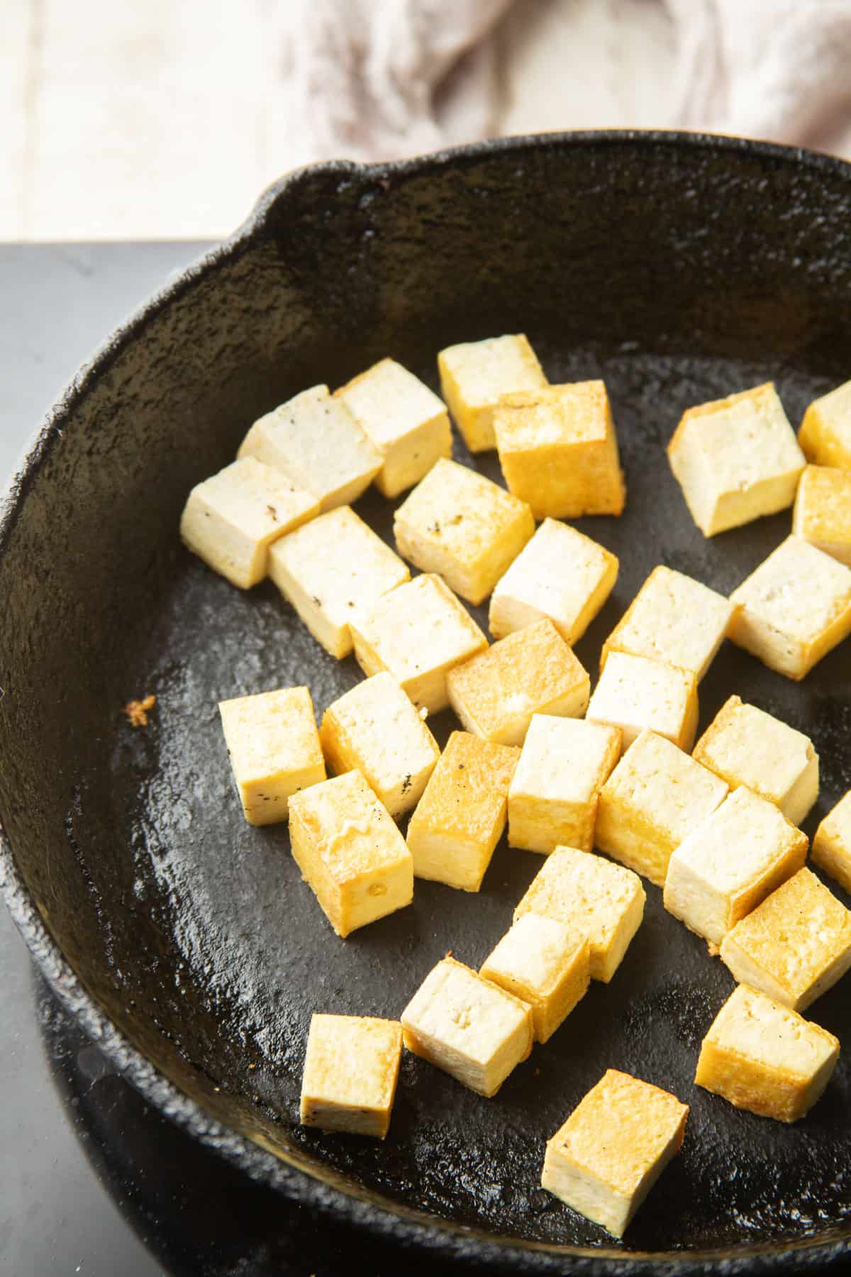 Tofu cubes cooking in a skillet.