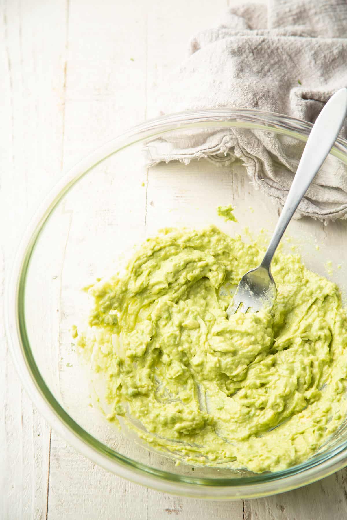 Avocado dressing in a mixing bowl with a fork.