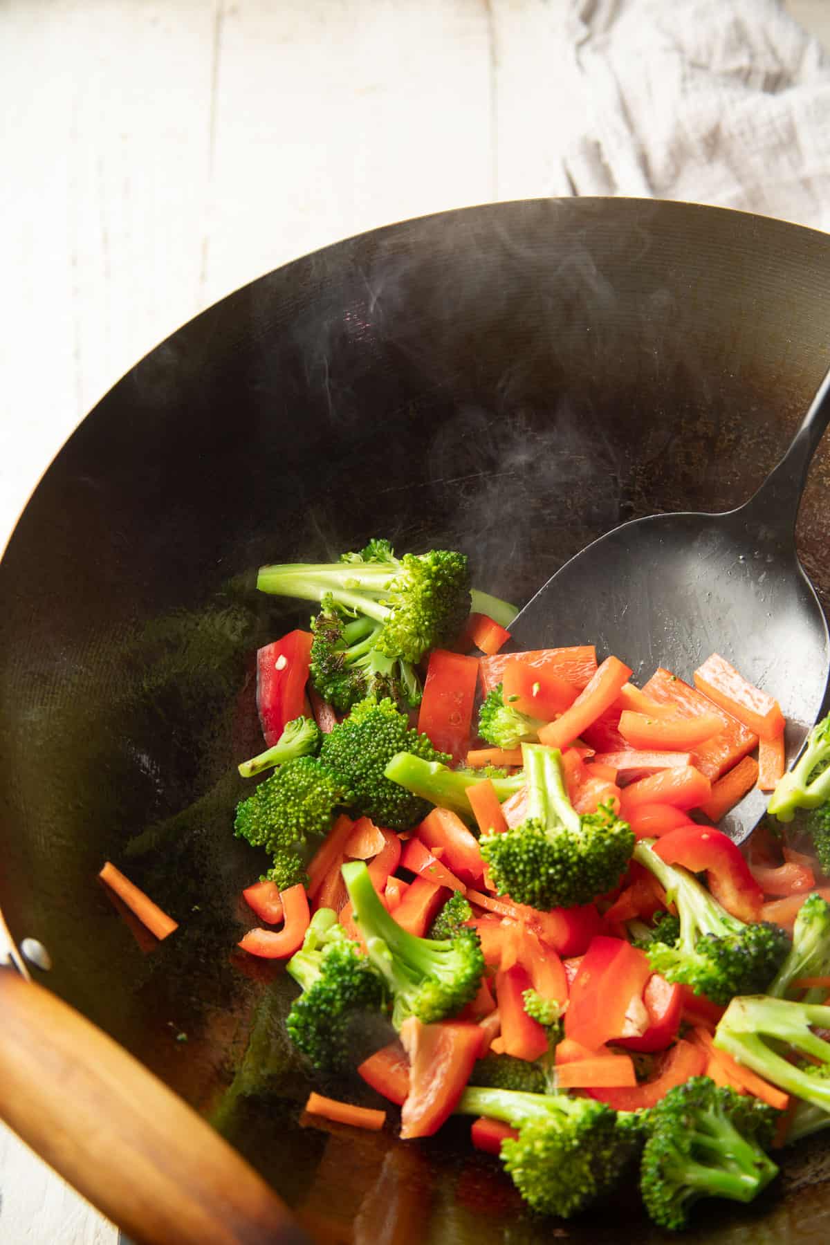 Broccoli, carrots and peppers stir-frying in a wok.