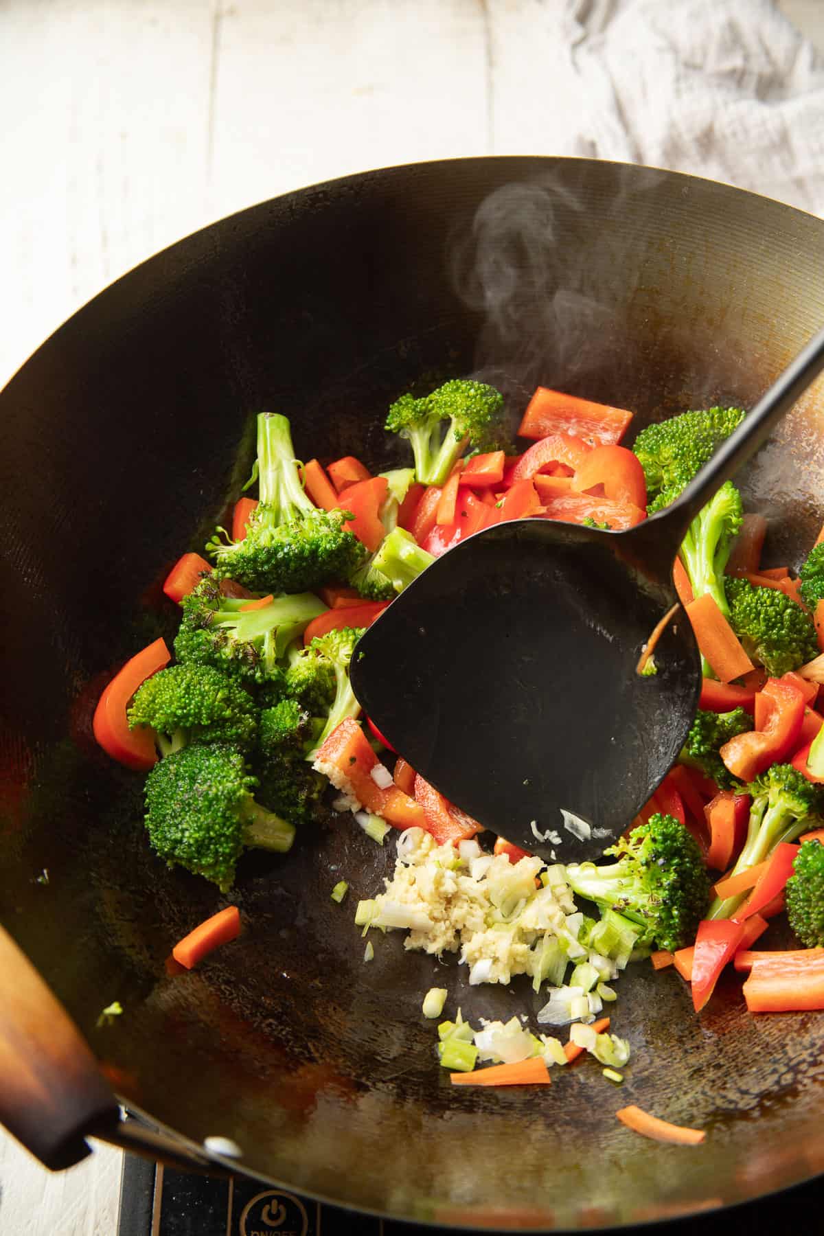 Ginger and garlic cooking in a wok with vegetables.