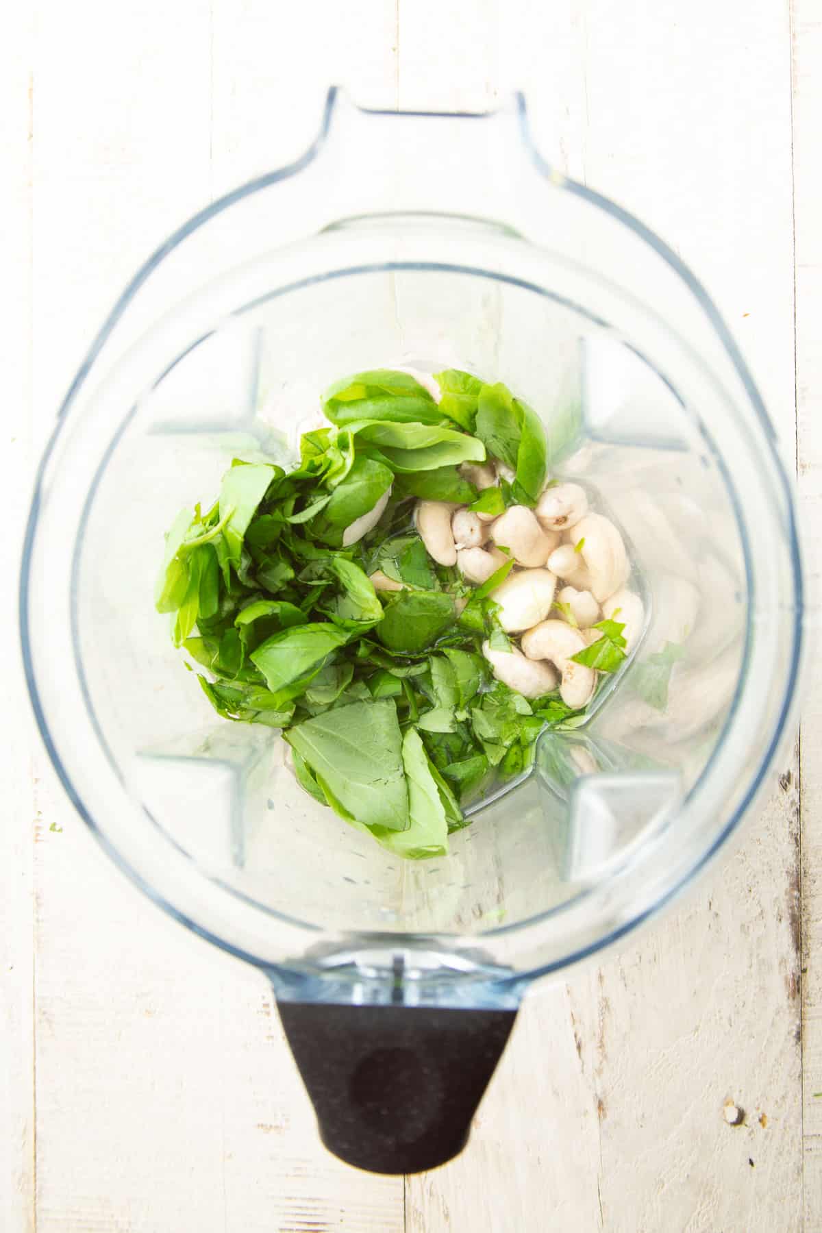 Ingredients for making cashew basil cream in a blender.