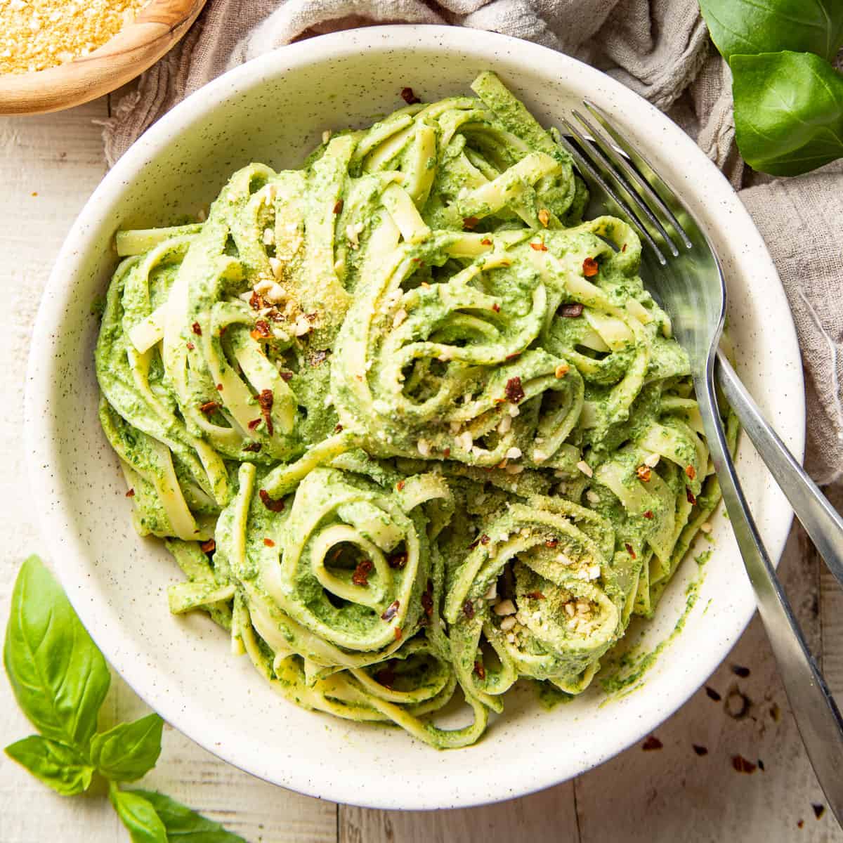 Vegan spinach pasta bowl with a fork and spoon.