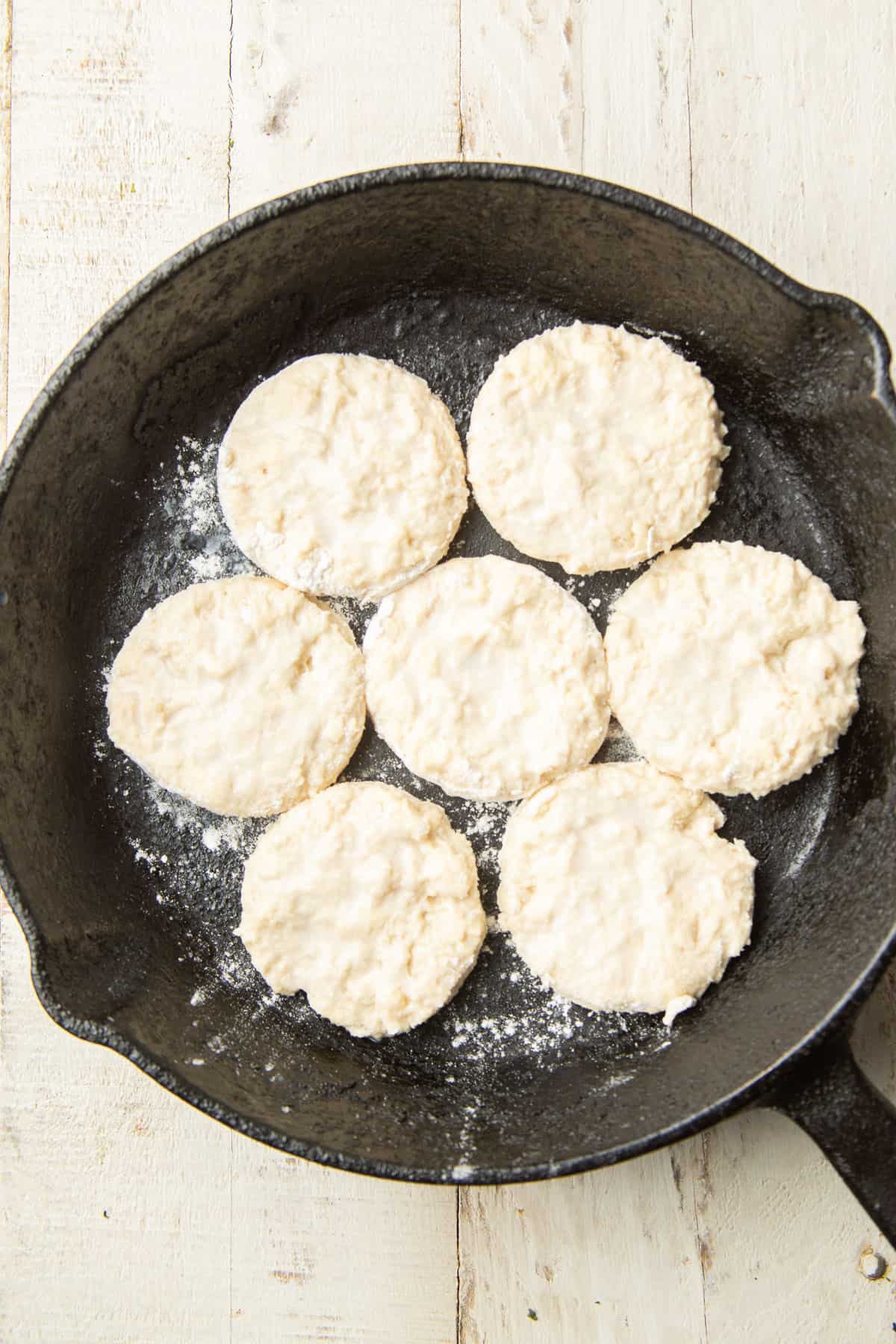Biscuit dough rounds in a cast iron skillet.
