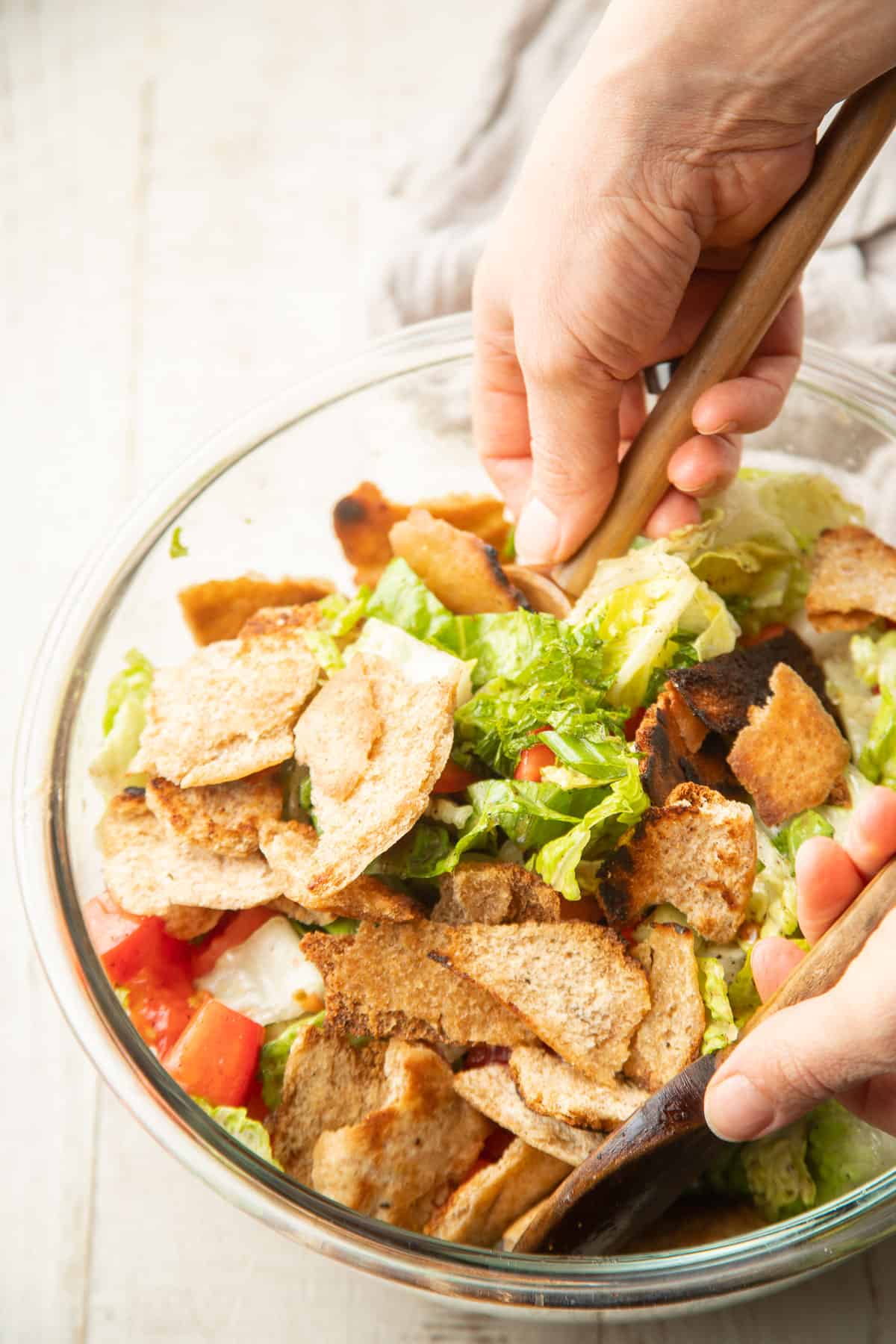 Hand stirring Fattoush Salad together in a mixing bowl.