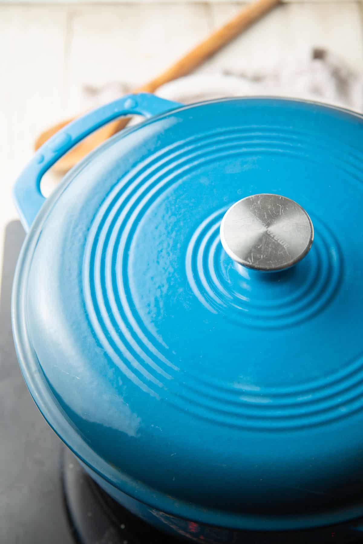 Blue Dutch oven with the lid on sitting on a stove top.