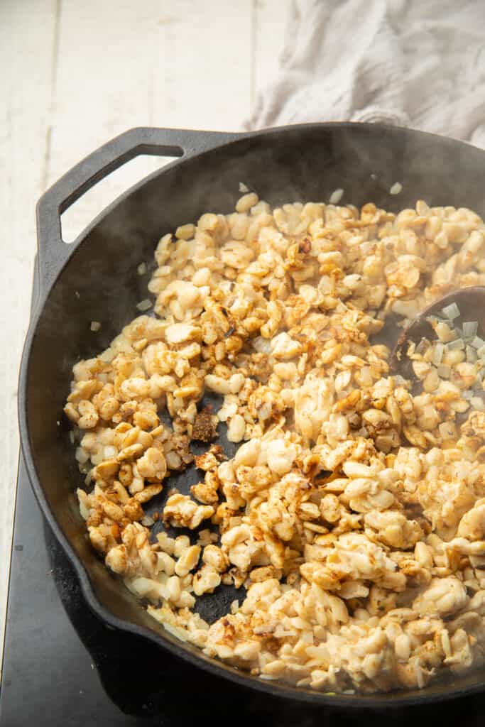Crumbled tempeh and spices cooking in a skillet.