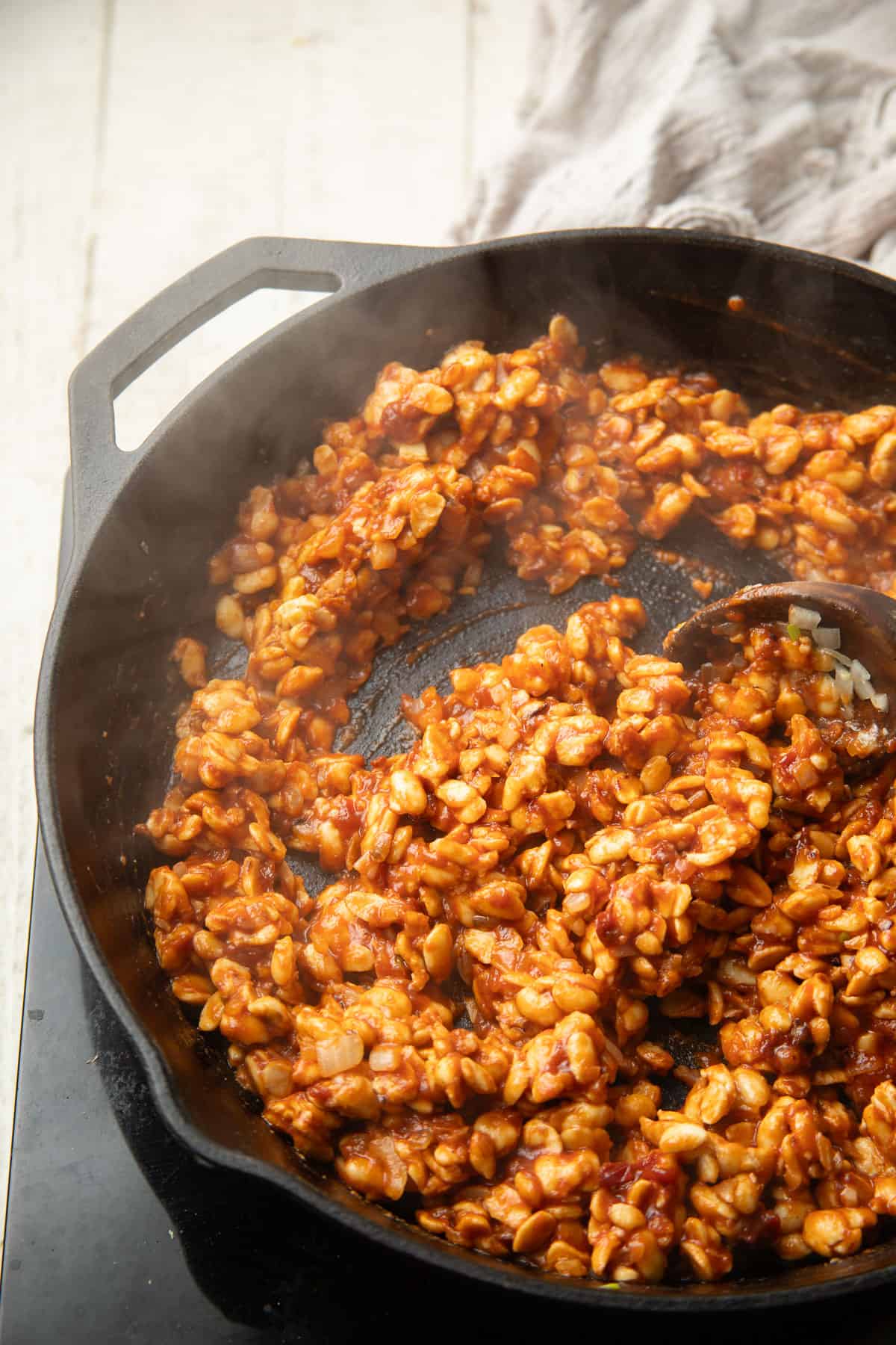Tempeh Taco filling cooking in a skillet with wooden spoon.