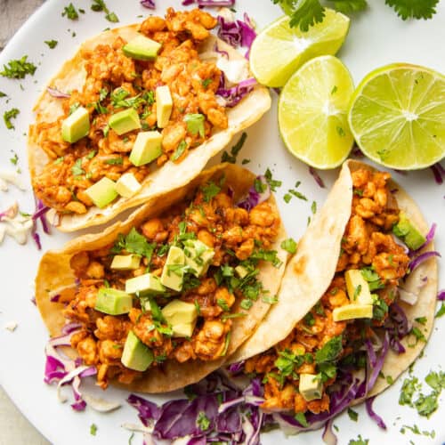Three Tempeh Tacos on a plate with lime slices.