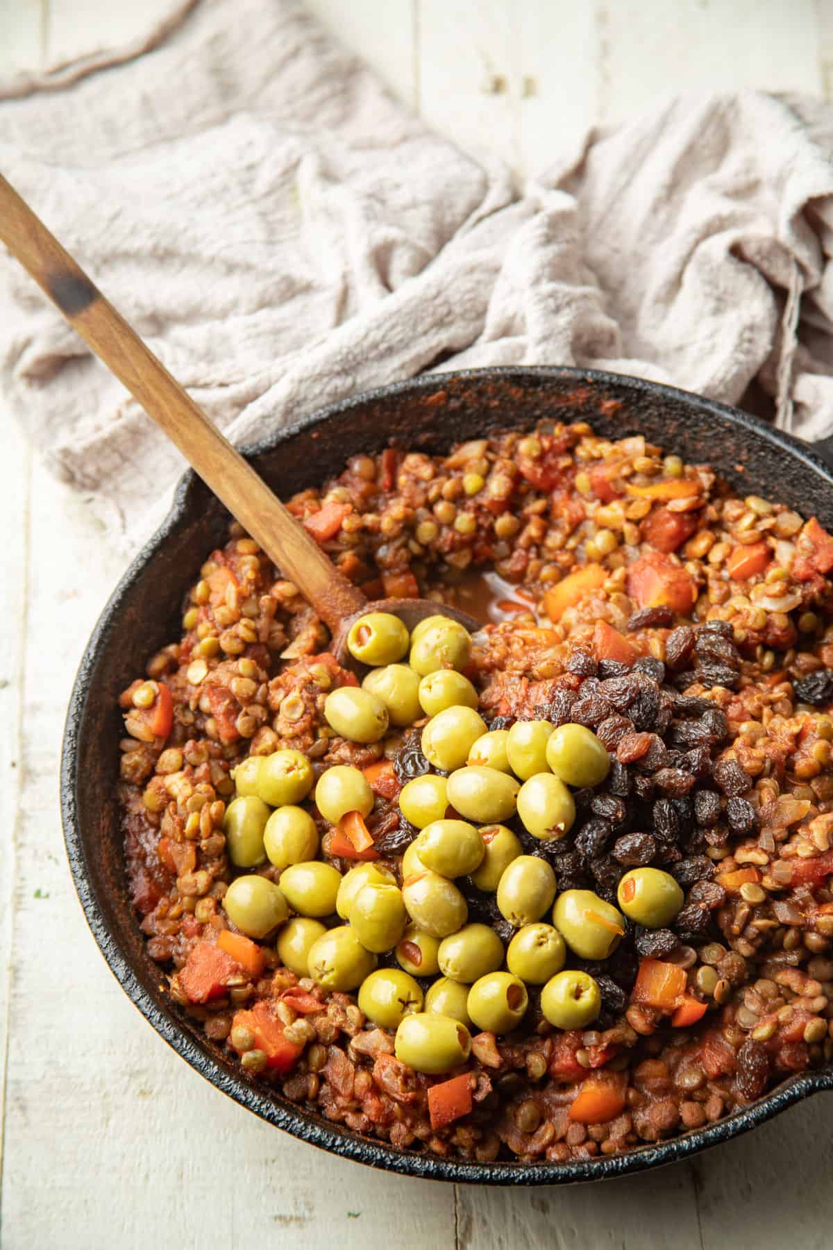 Skillet of Vegan Picadillo with olives and raisins on top.