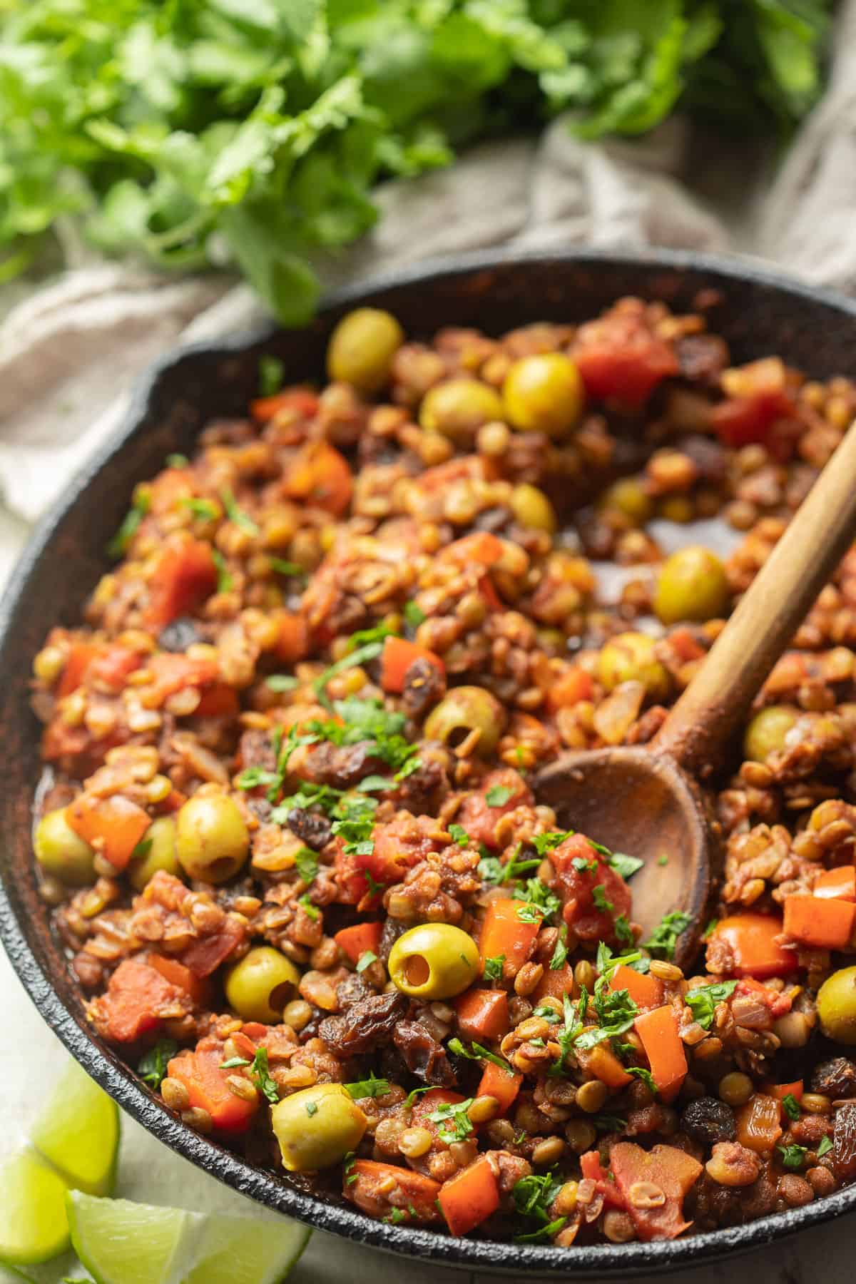 Skillet of Vegan Picadillo with a wooden spoon.