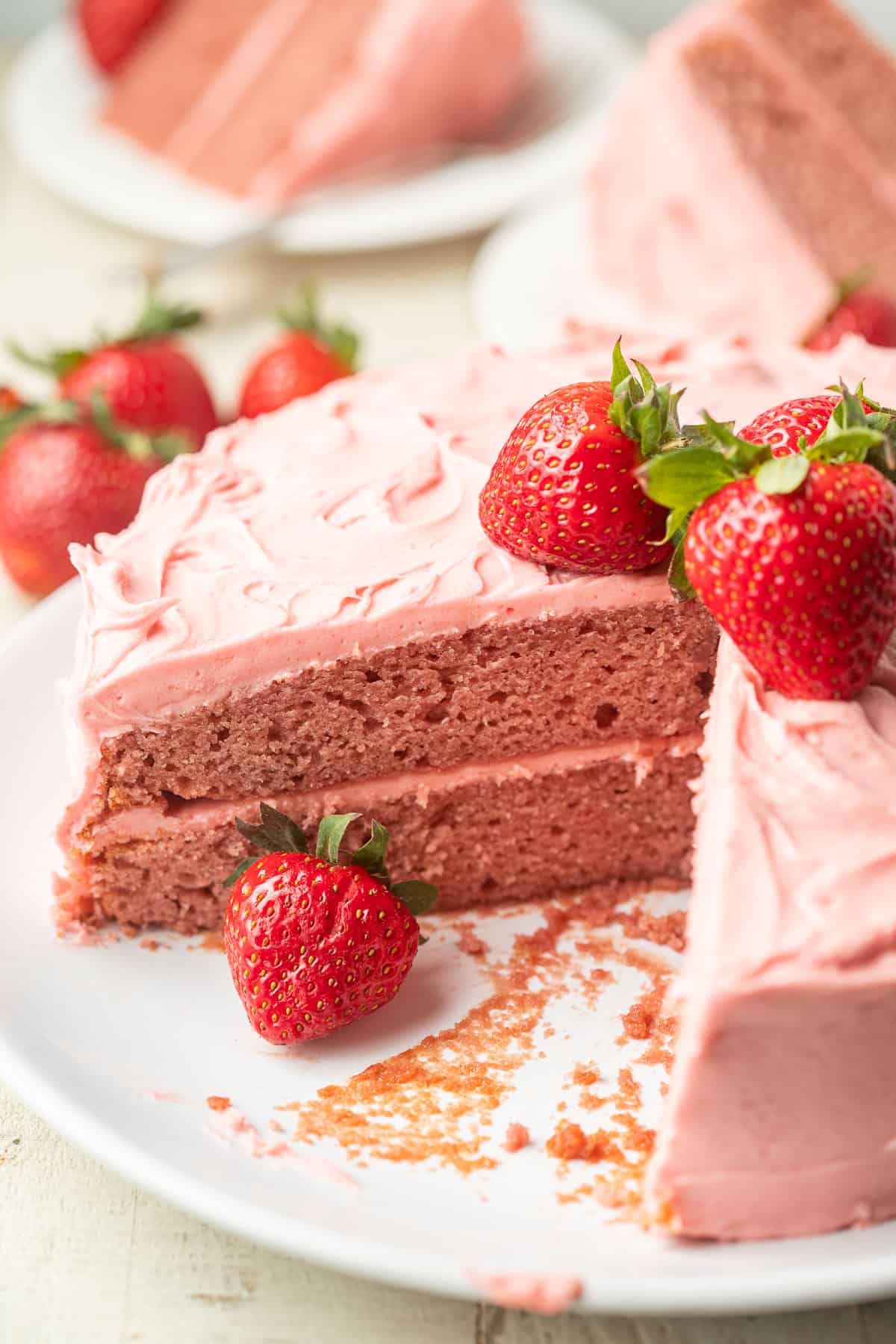 Vegan Strawberry Cake with a slice cut out and fresh strawberries on top.