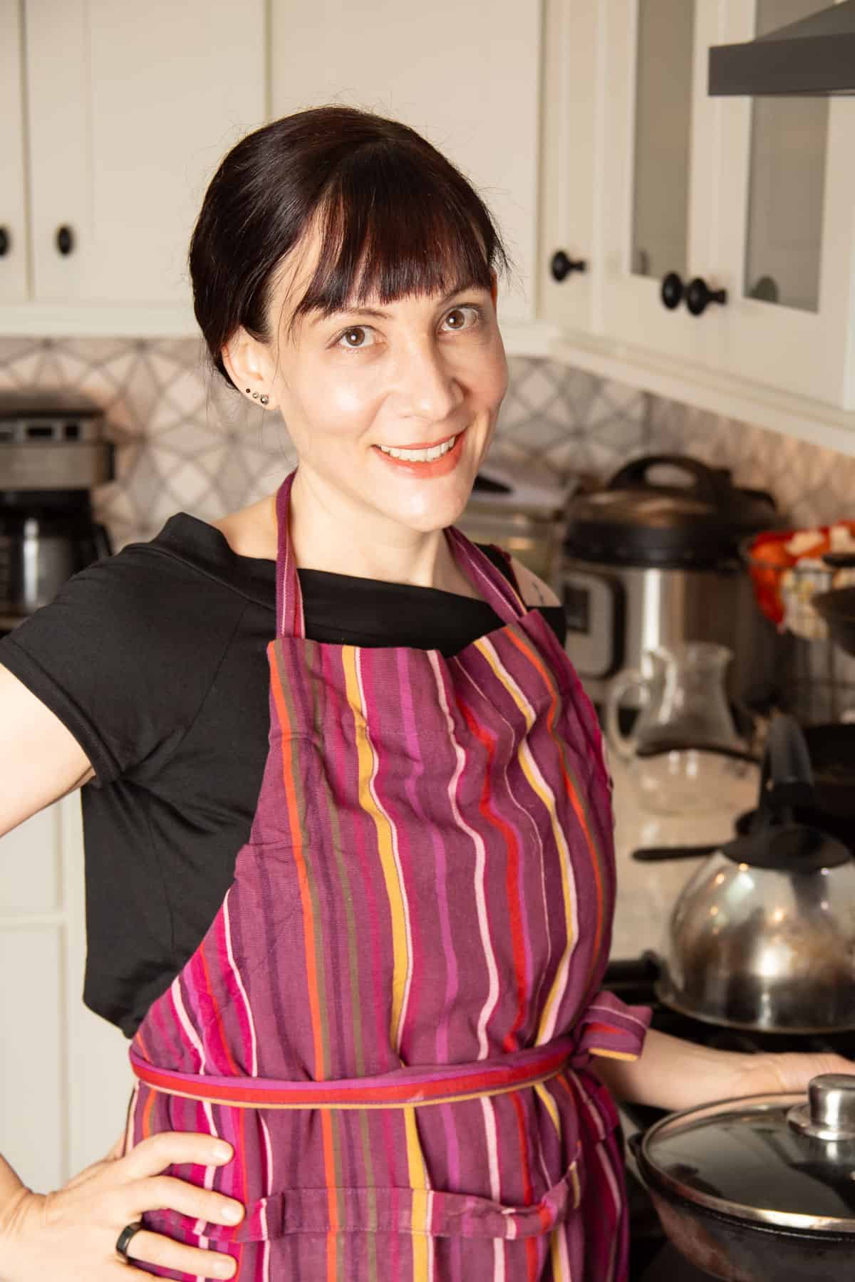 Alissa wearing an apron standing in the kitchen.