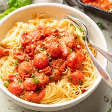 Bowl of Cherry Tomato Pasta with fork and spoon.