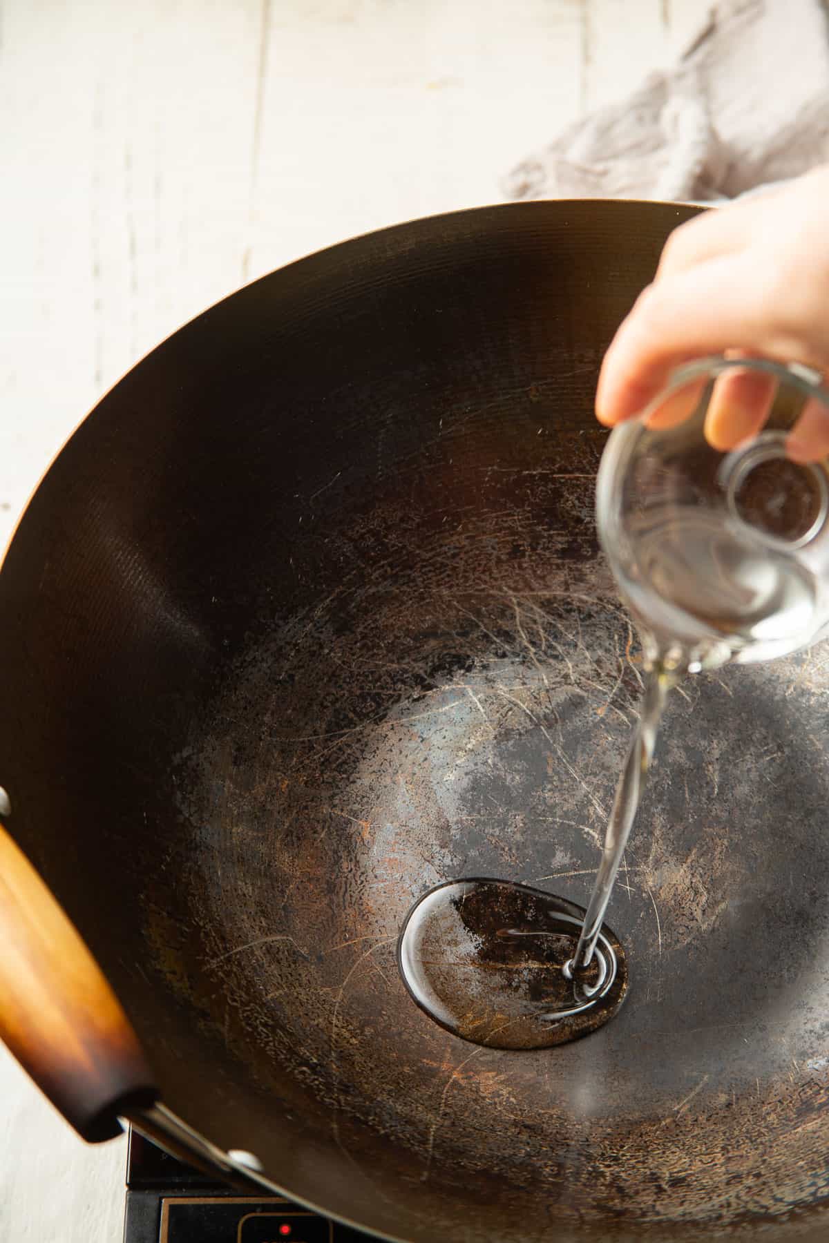Hand pouring oil into a wok.